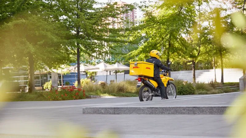 a male dhl employee doing his deliveries on a motorbike