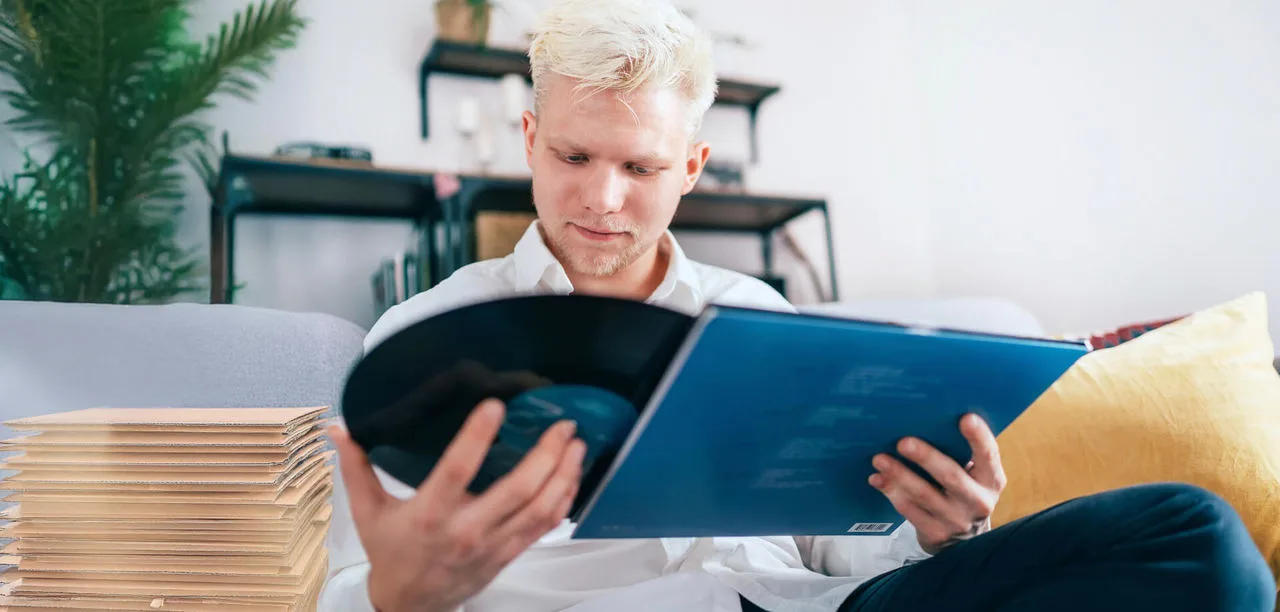 Blonde haired man packing up a collectable record into shipping boxes