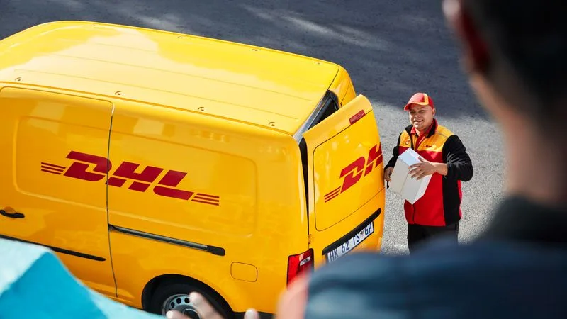 dhl express employee retrieving a package from his delivery van