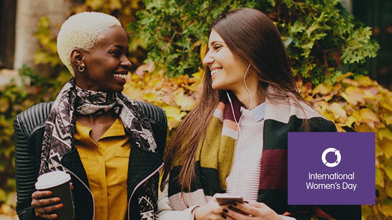 Two women smiling at eachother with 'International Women's day' logo