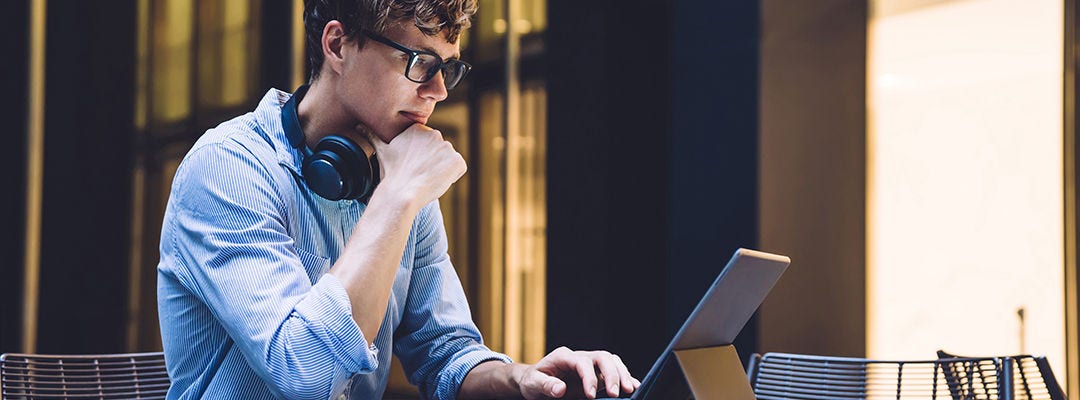 Businessman in formal wear watching online webinar during distance work with startup project on portable pc connected to 4g wireless, male trader in spectacles checking information on website