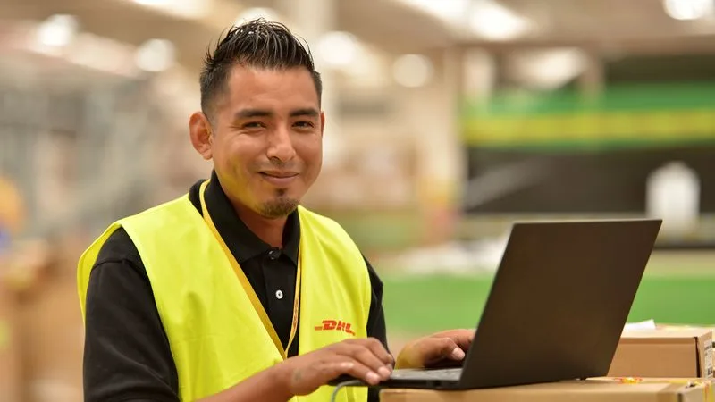 smiling dhl express employee in sorting warehouse