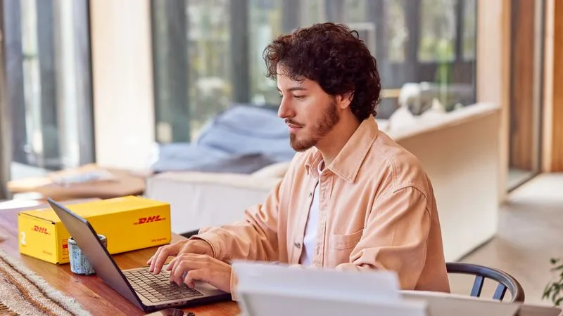 A male customer uses his laptop at home to pay his invoice via DHL MyBill desktop.