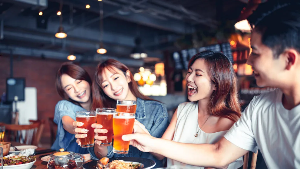 happy young group dining and drinking beer at restaurant