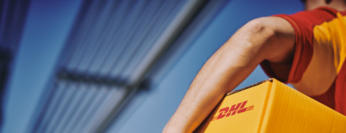 A DHL courier confidently carries a branded yellow package across a modern bridge, symbolizing speed, reliability, and global logistics connectivity. The image conveys professionalism and efficient service in parcel delivery.