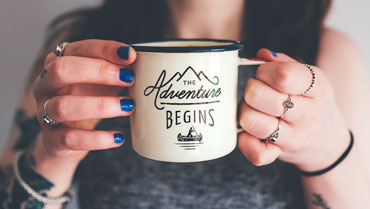 Woman holding a 'the adventure begins' mug