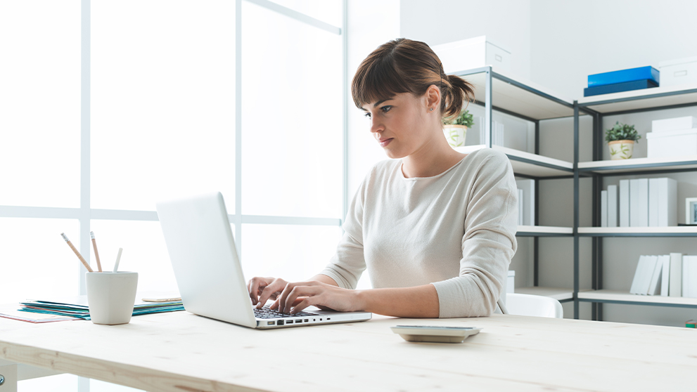 woman typing and looking at a laptop screen