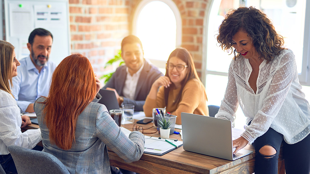 people sitting around a table looking at laptop screens