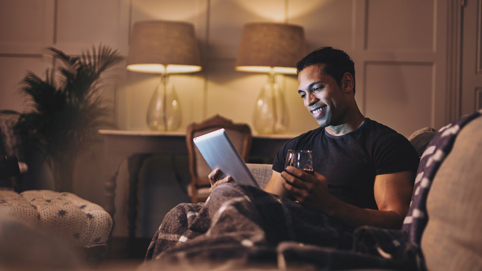 Man reading on a table with a glass of red wine