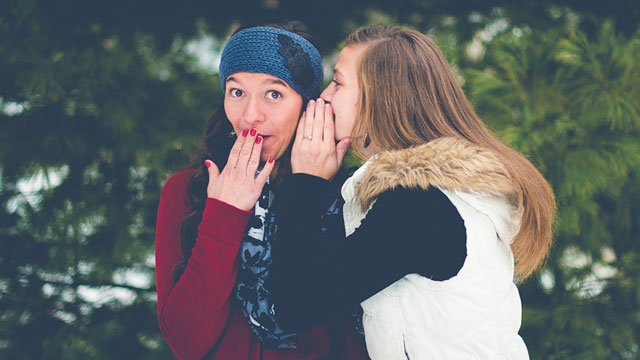 one woman whispering in another woman's ear