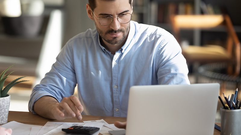 man in glasses looking at laptop screen