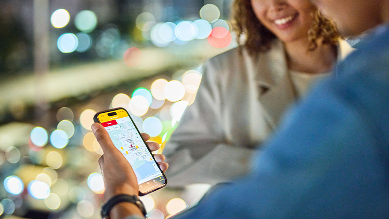 Two people are looking at a phone to track their parcel on a map