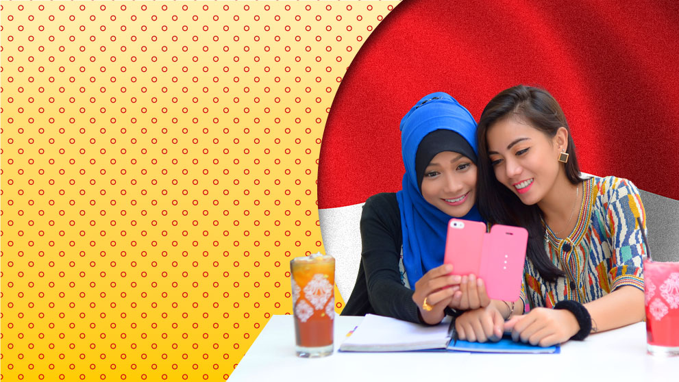 two women smiling at mobile phone screen