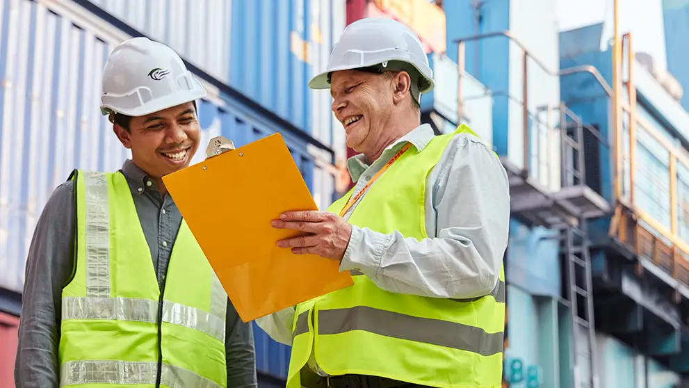 two men in hard hats looking at a clipboard