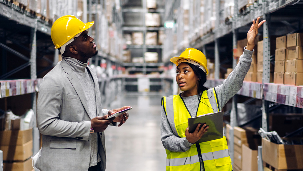 man and woman in hard hats in a warehouse