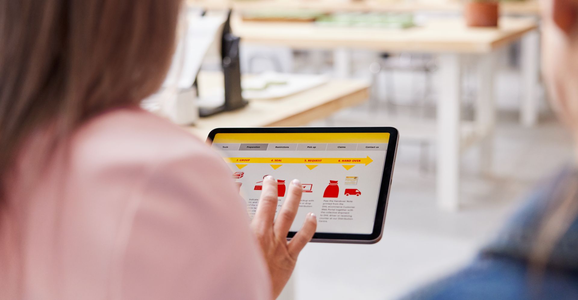 Seseorang yang memeriksa solusi pengiriman DHL di tablet selama konsultasi