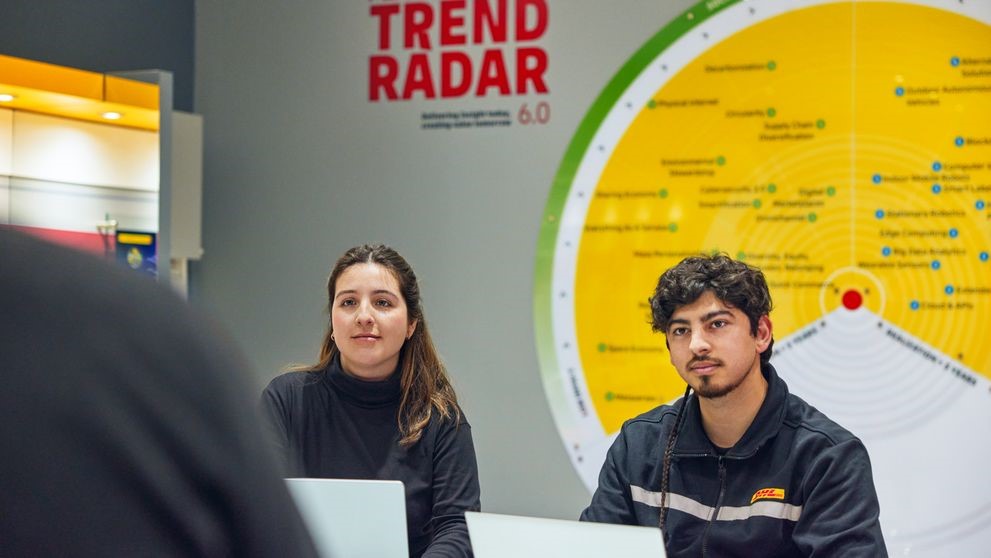 two dhl employees discussing logistics trends in front of a trend radar wall