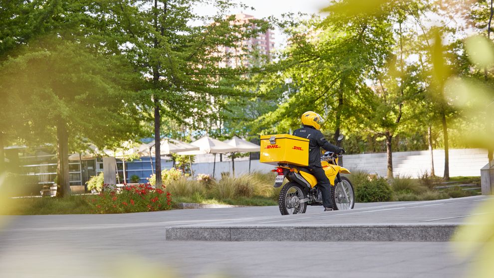 DHL express employee delivering a parcel in Pakistan while riding a motorcycle