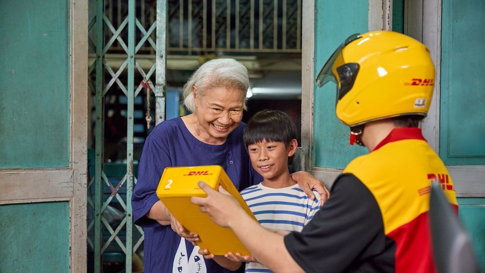 a grandmother and grandson receiving a parcel with japanese products from a dhl employee