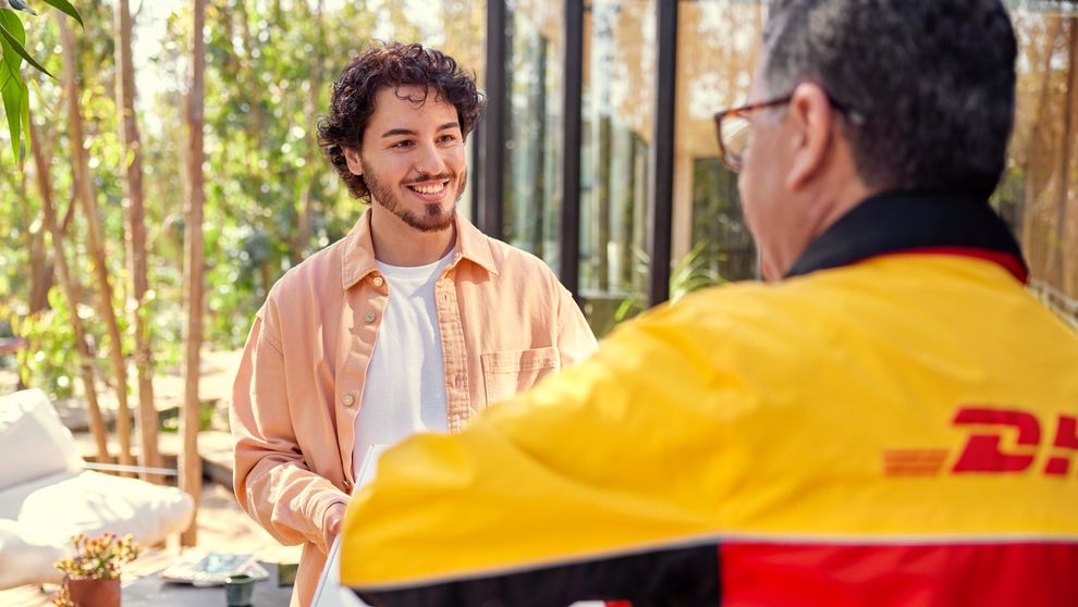 A man receiving a package from a DHL employee.