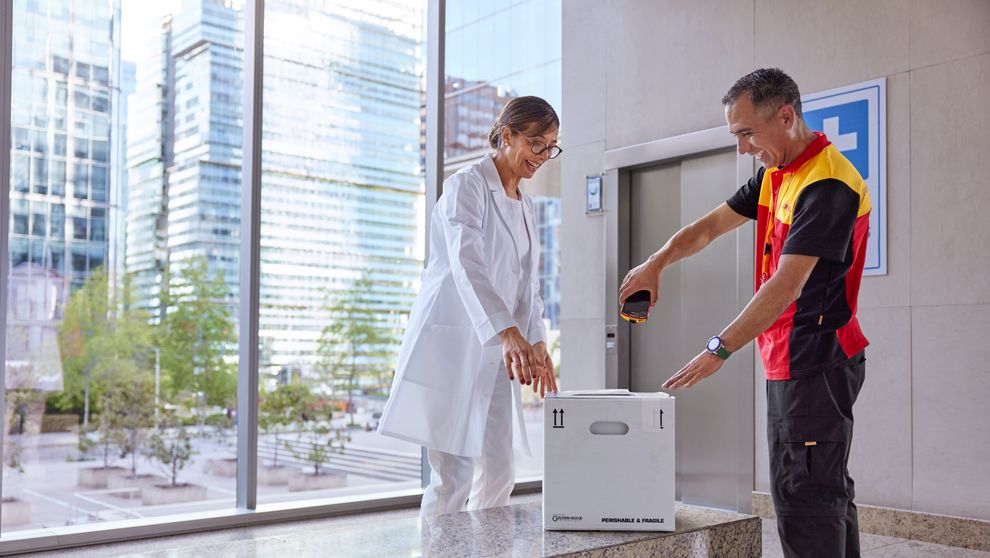 DHL employee is scanning a delivery next to a female customer working in the medical sector