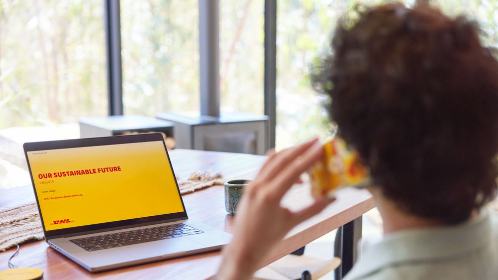 a young man using his laptop at home with the screen showing a slide on sustainable future