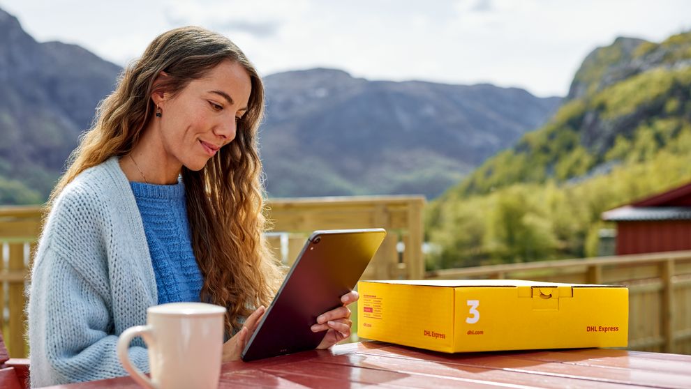 female customer browsing on tablet with DHL parcel