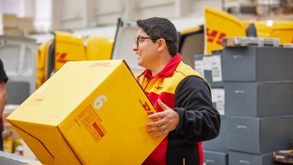 A DHL employee handling a large parcel.