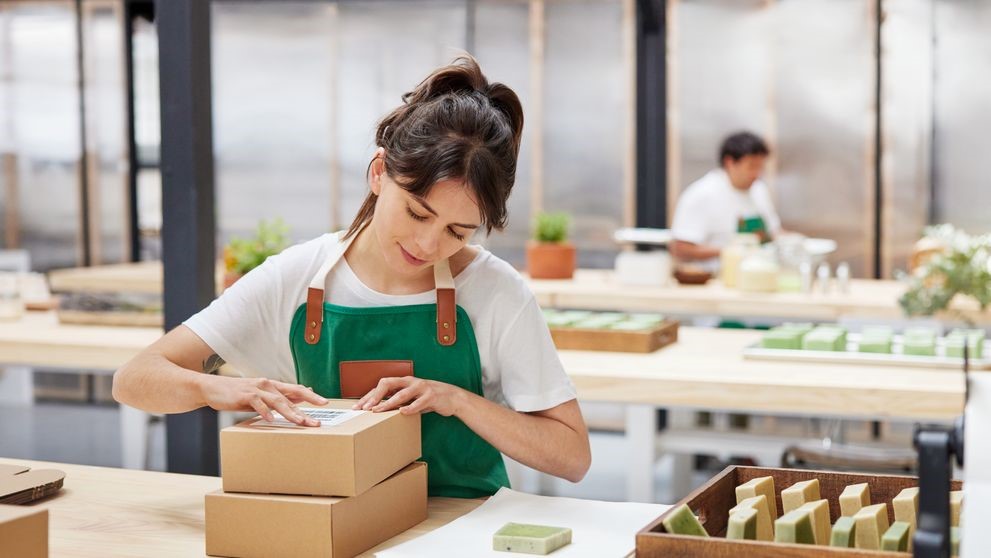 A female employee sticking a shipping label on a small packaging.